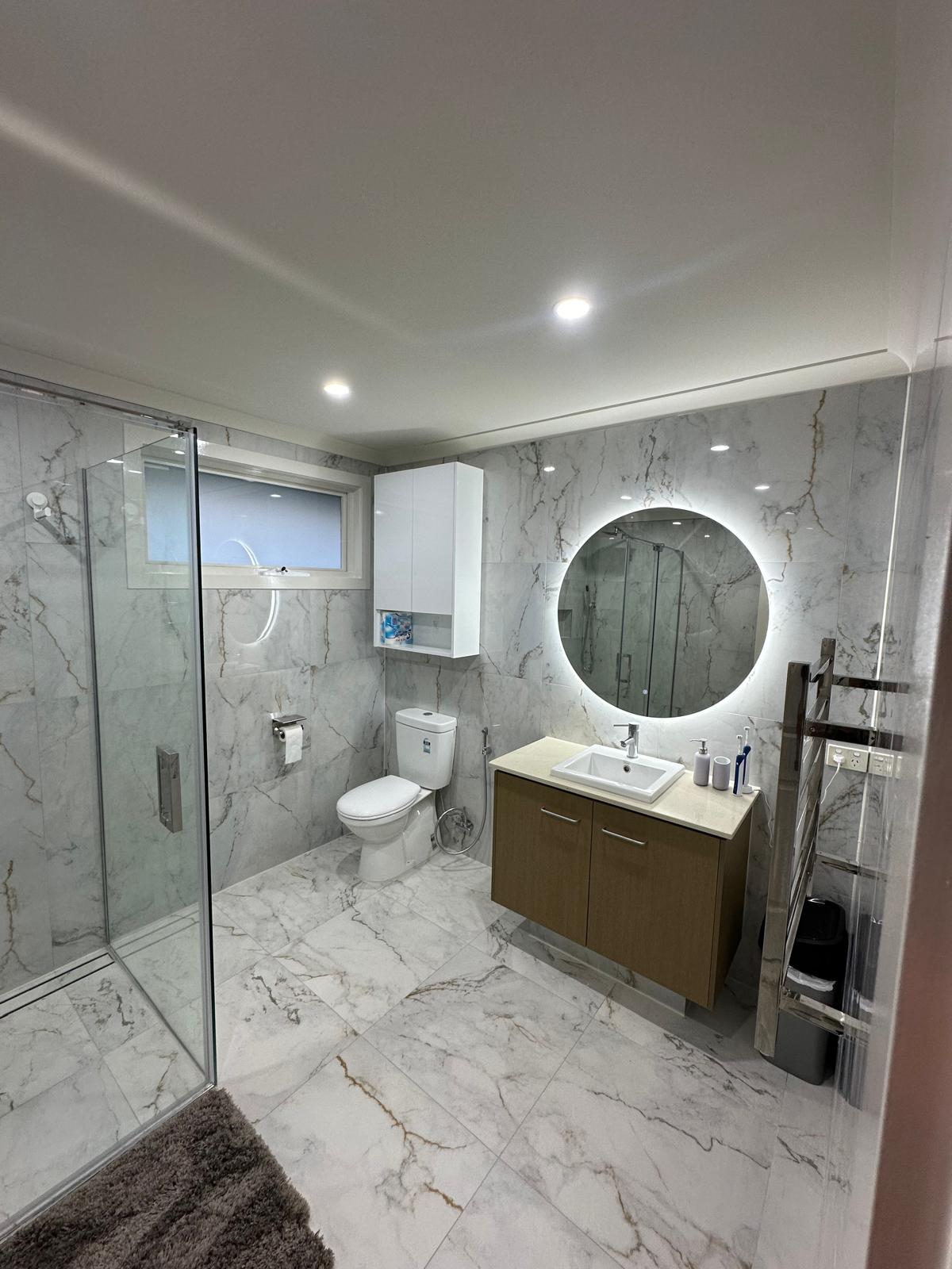 Contemporary bathroom design with round LED mirror and floating vanity